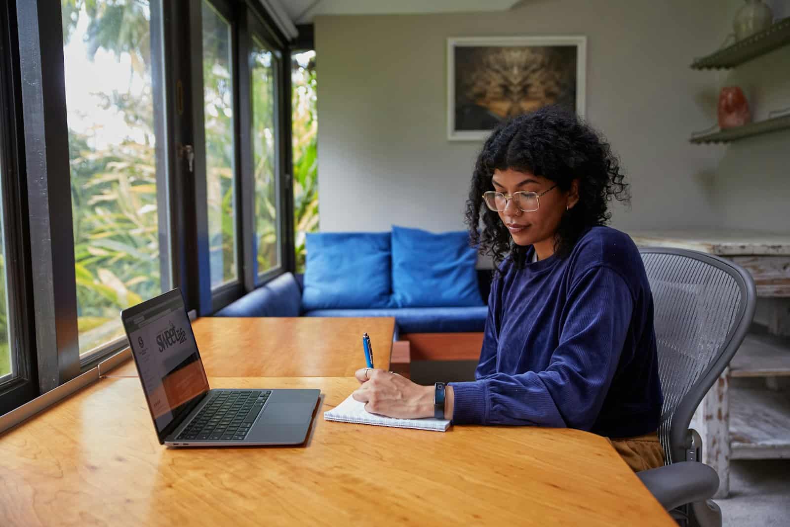 A young woman working on a laptop at a table at home.