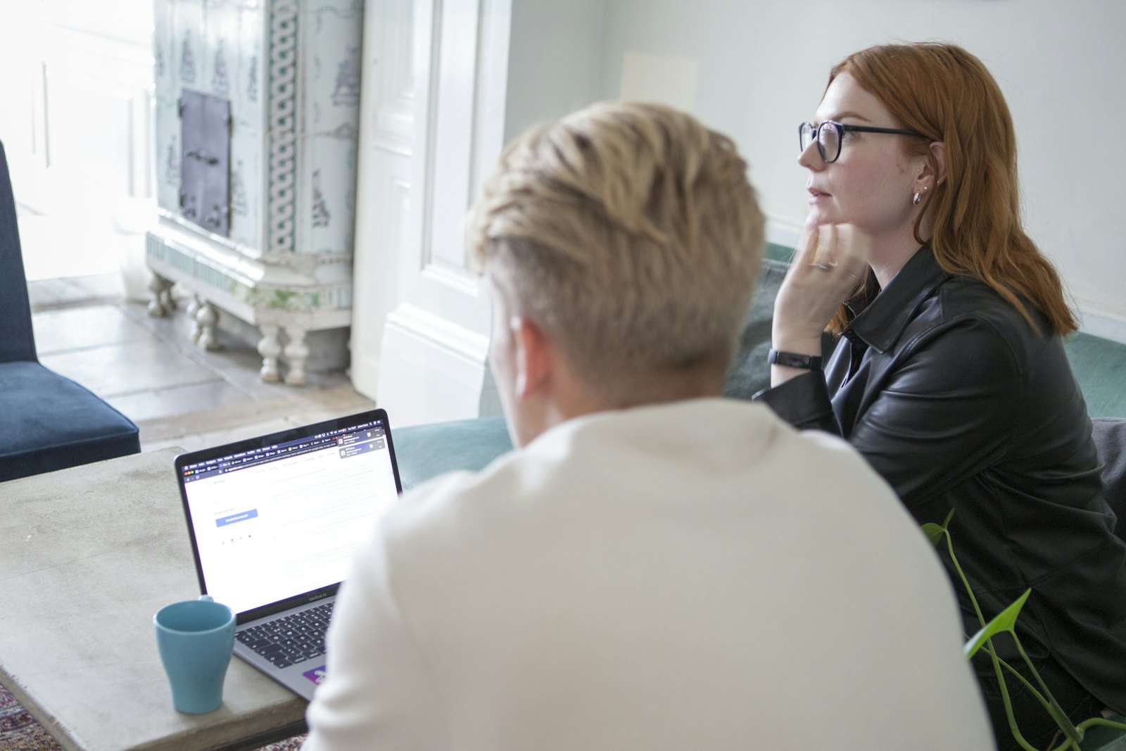 A man and a woman sit together at a table, reviewing information on a laptop.
