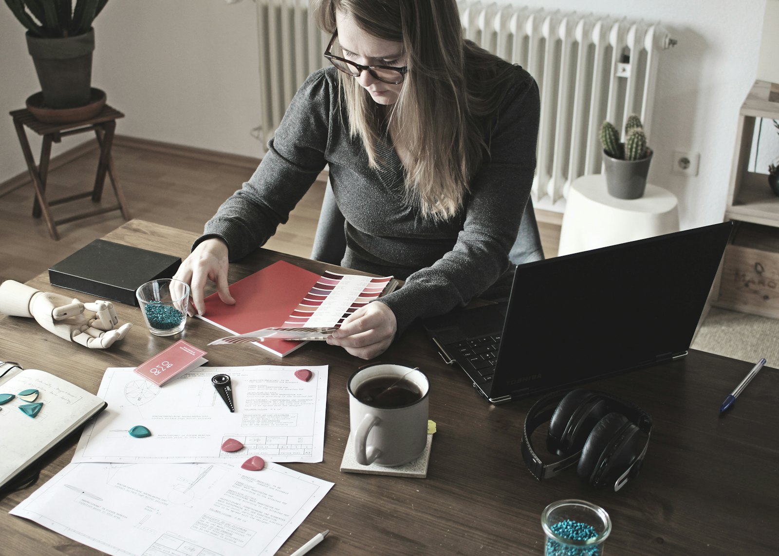 A woman at a desk sorts through receipts and statements next to her laptop to track her spending.