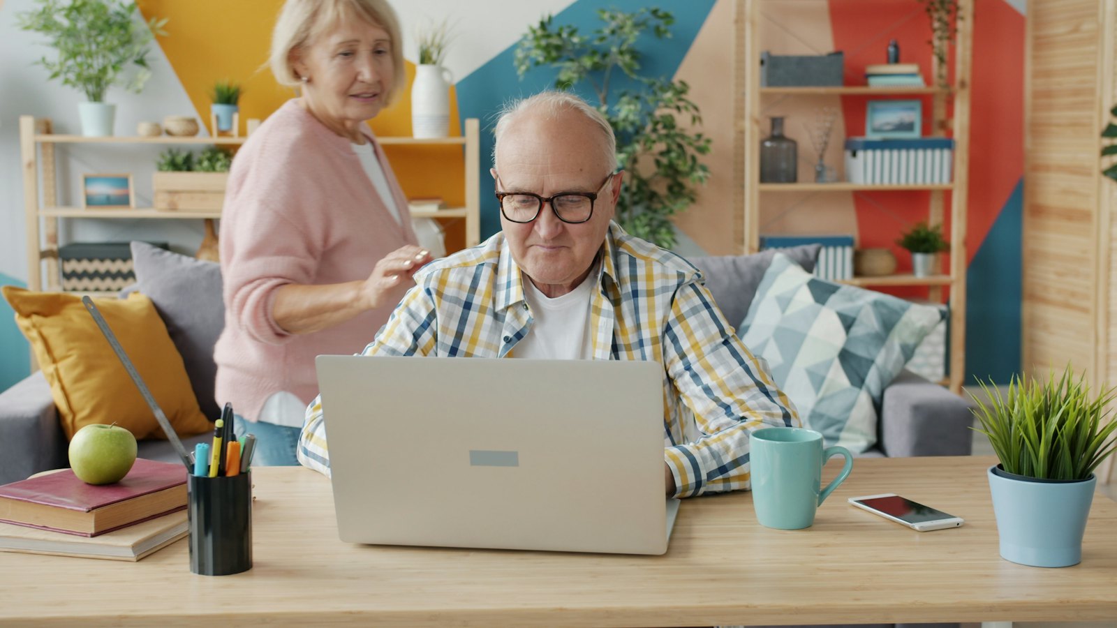 An older couple sits together in their living room working on a laptop